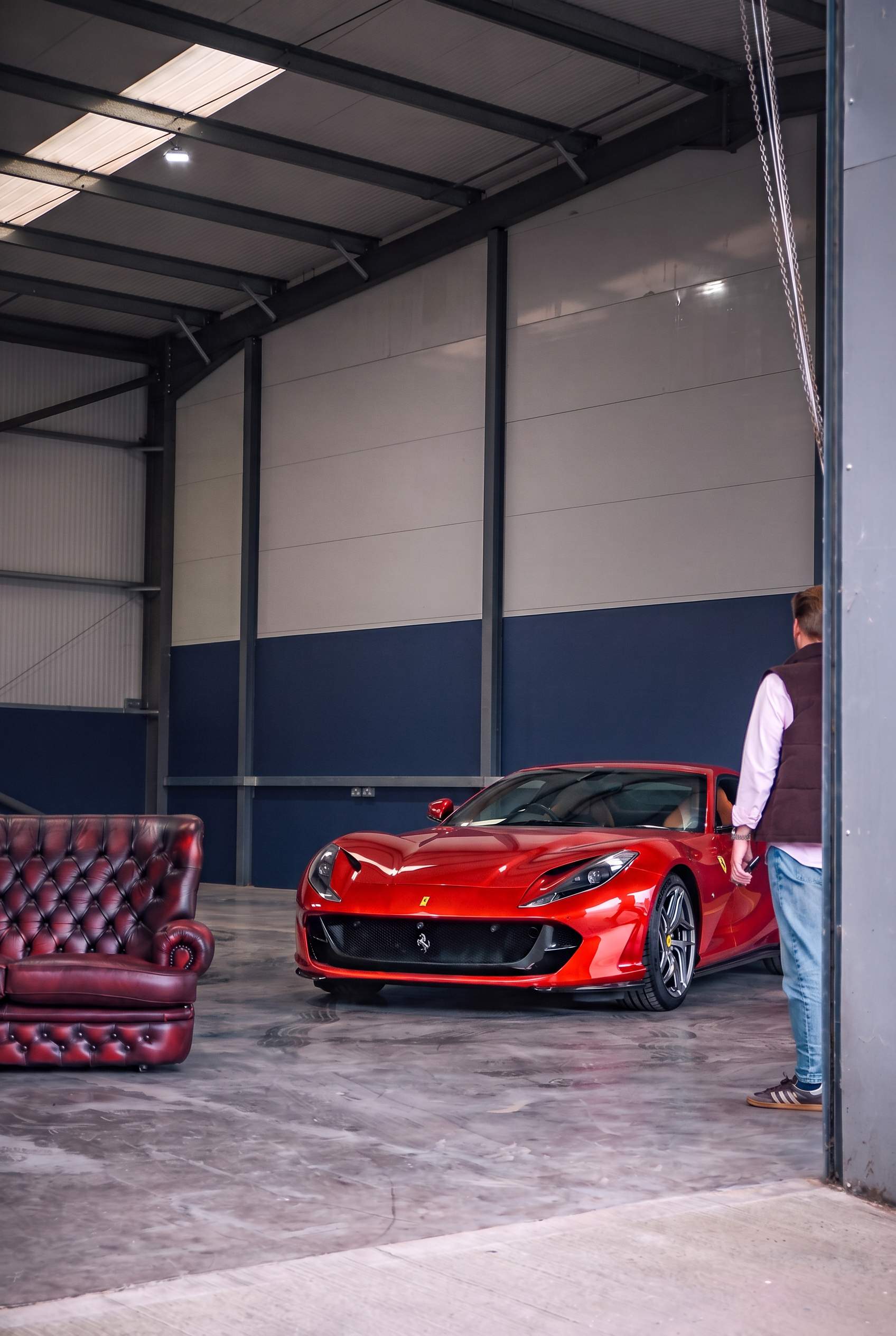 A red Ferrari 812 inside the Mallards showroom beside a leather Chesterfield