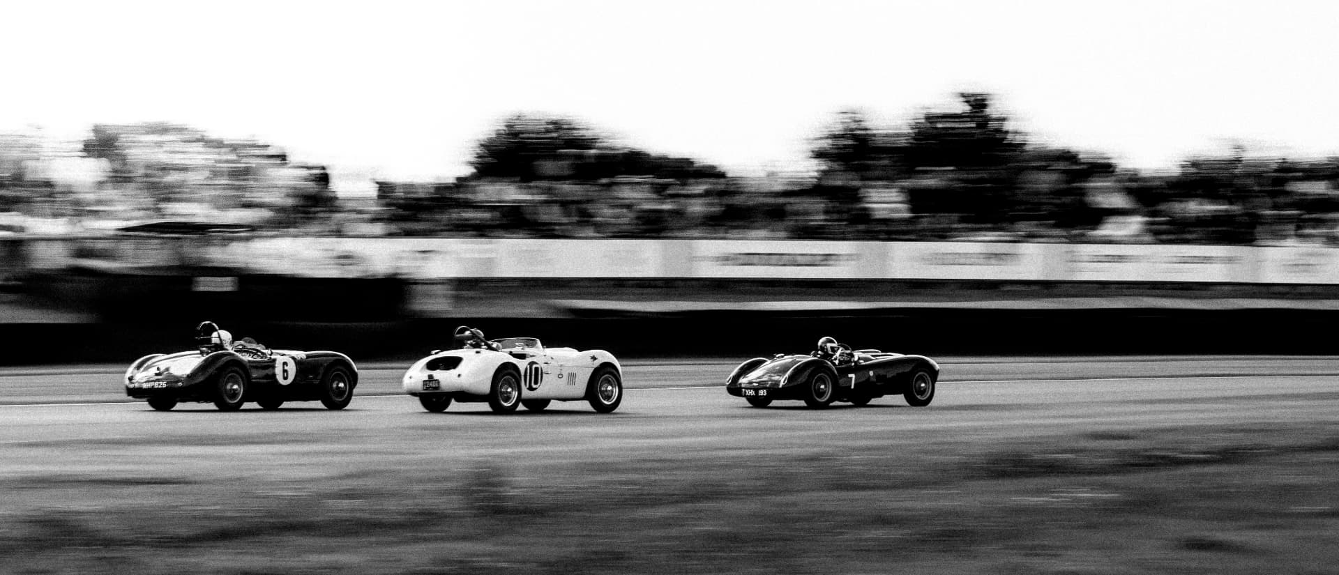 Three classic sports racers running nose to tail, in black and white
